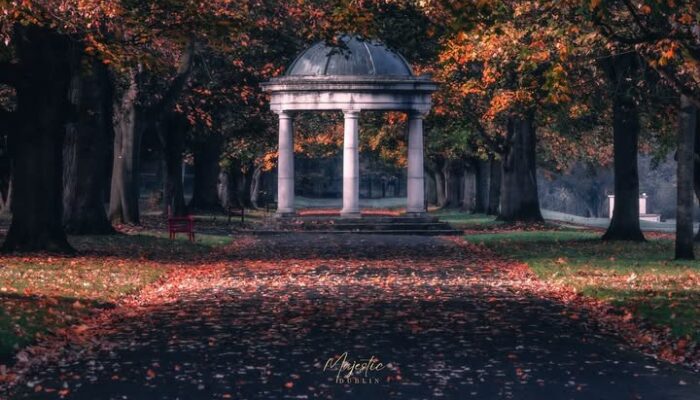 Autumnal path through St Stephen's Green in Dublin, one of the best free things to do in Dublin, leading to a classic domed bandstand amid glowing orange trees and fallen leaves.